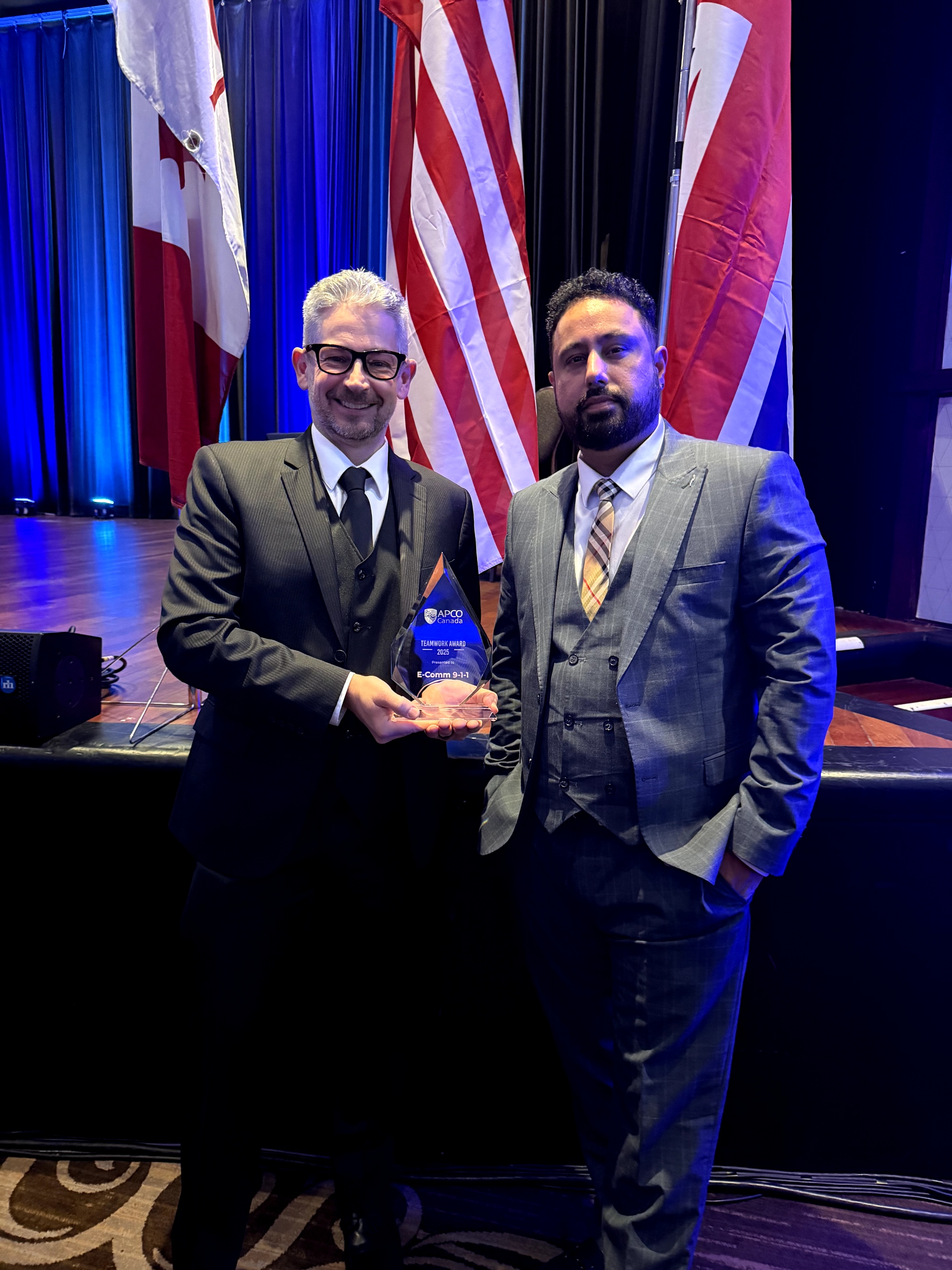 Fire Charge Dispatcher Corey Kelso and Fire Dispatcher Gurvinder Sandhu smiling for the camera with the APCO Team Award at the APCO Canada 2025 Awards Reception.